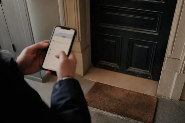Seuil de porte d’un appartement sans colis, suivi de livraison consulté sur un smartphone