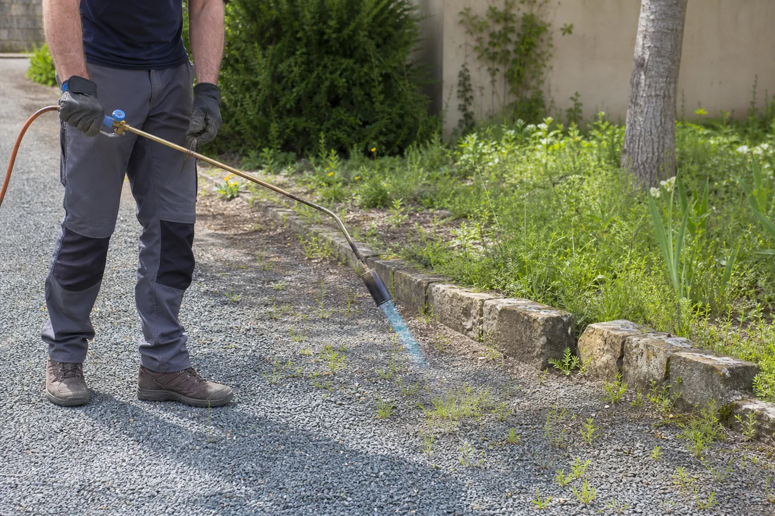 Désherbeur thermique utilisé sur une allée en gravier pour éliminer les mauvaises herbes