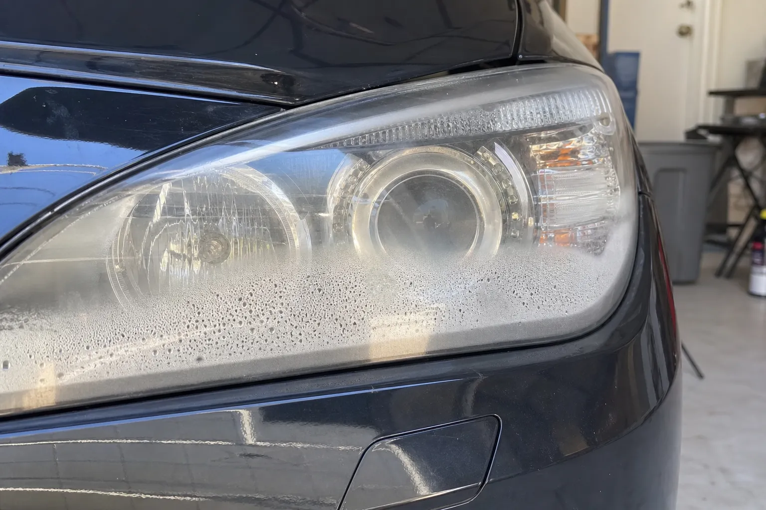 Phare avant de voiture vu de près avec de la buée et des gouttelettes d'eau à l'intérieur de l'optique