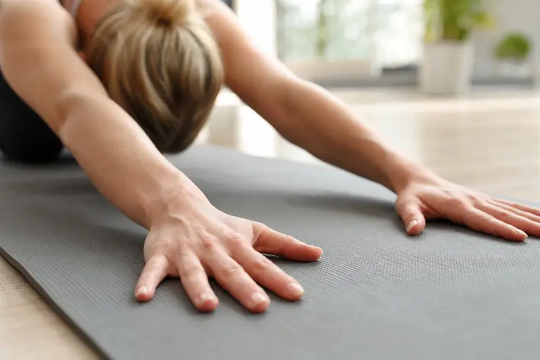 Mains en appui sur un tapis de yoga pendant une posture, dans une salle lumineuse
